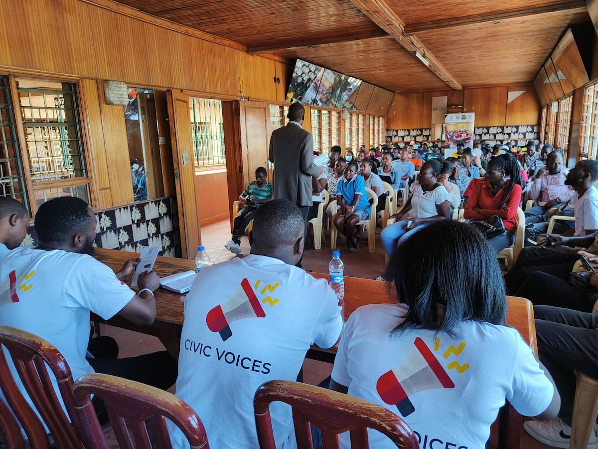 Equipe da Civic Voices conduzindo uma sessão comunitária em ambiente interno.